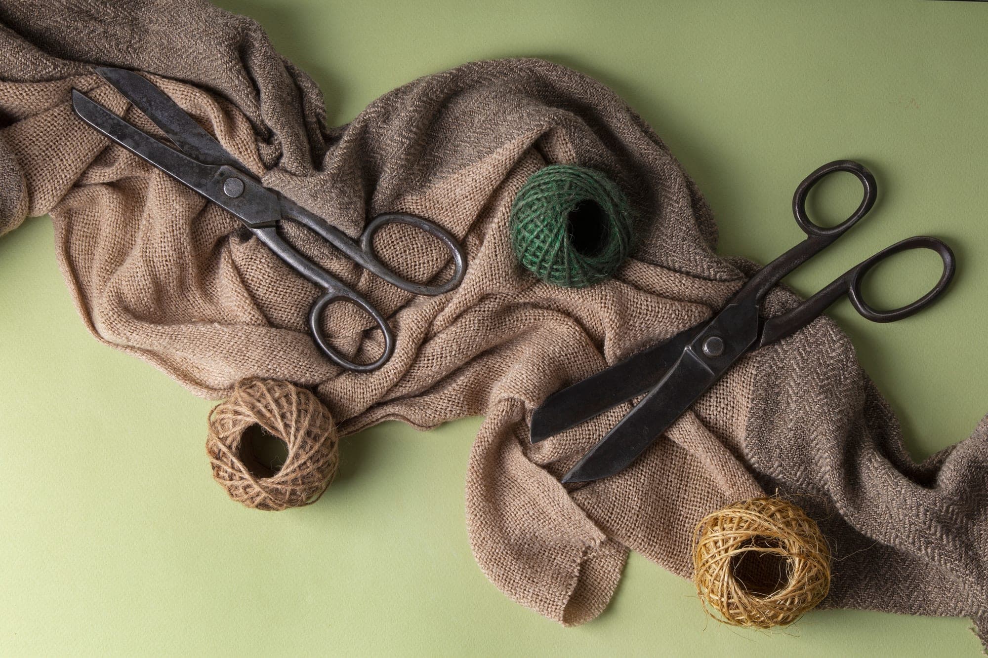 Two pairs of vintage scissors on jute cloth with balls of twine.