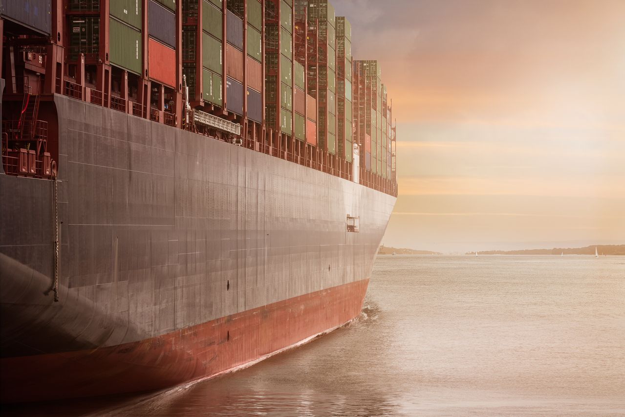 A loaded container ship under way at dusk.