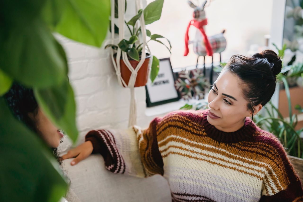A striped knitted sweater worn in a plant-filled room.
