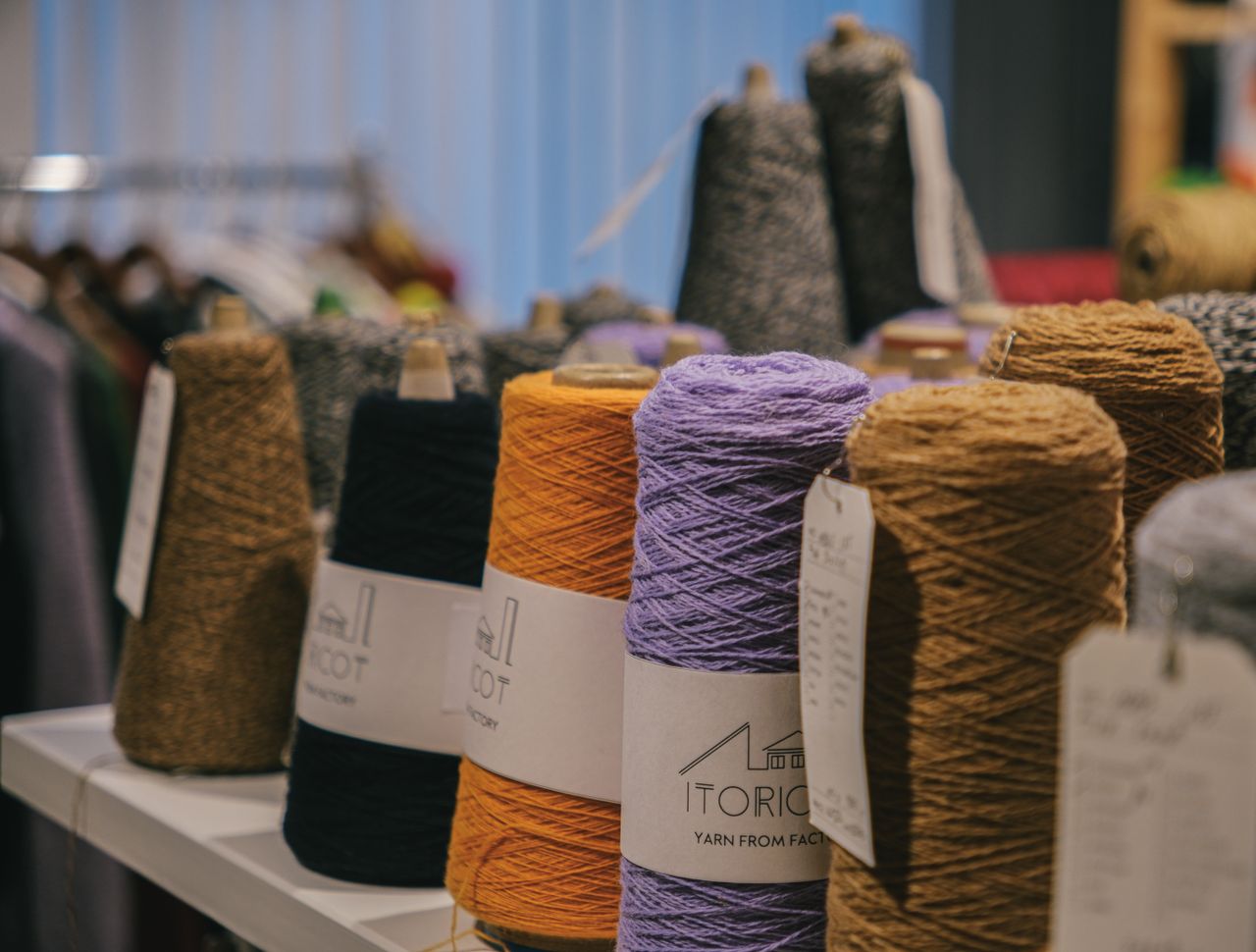 Labelled yarn cones lined up on a development shelf.
